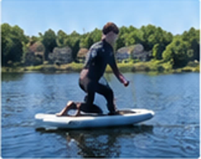 Rider kneeling on the eFoil board on flat lake water